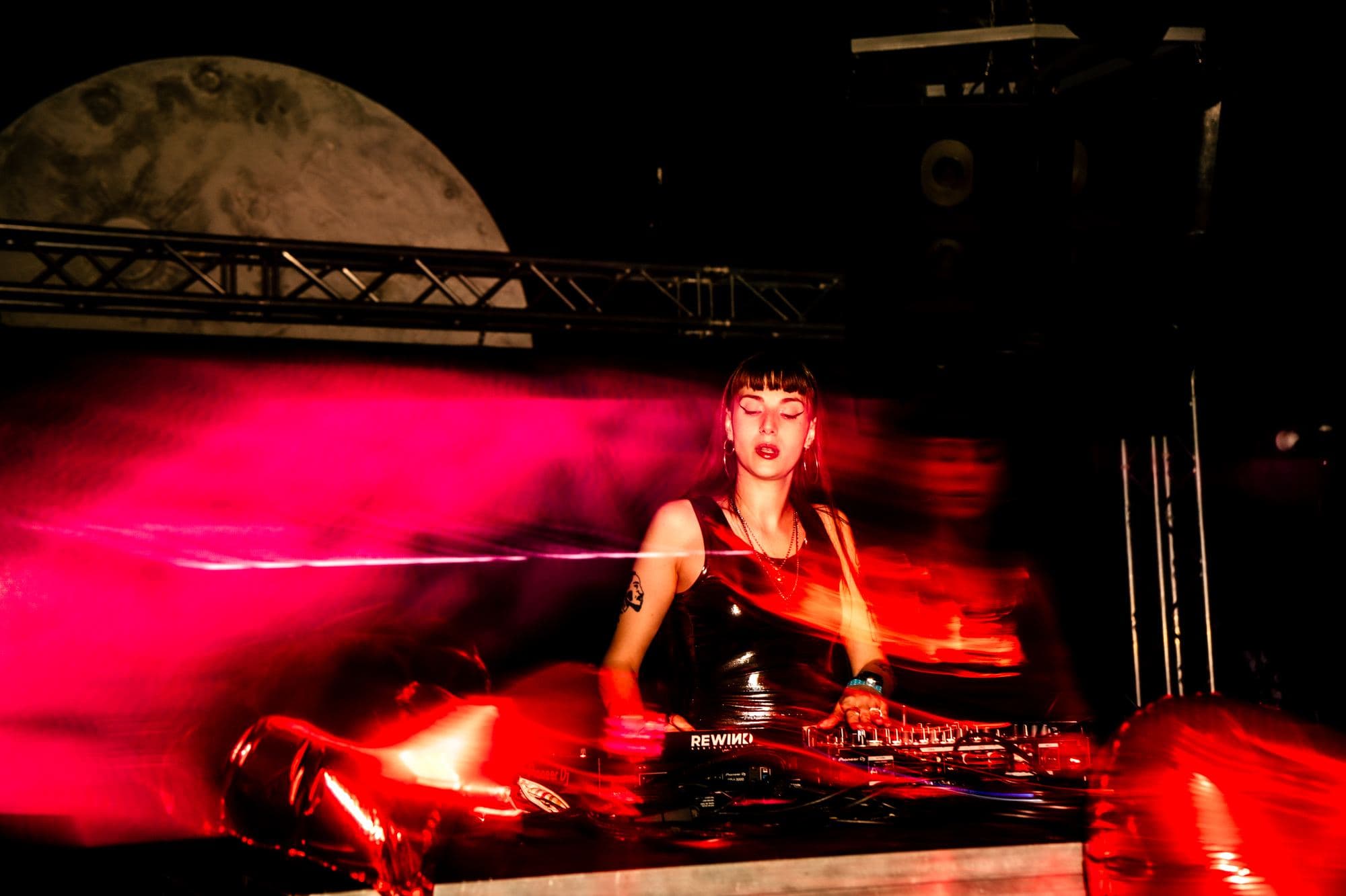 The Moon Club stage with the giant moon behind a DJ, in red light